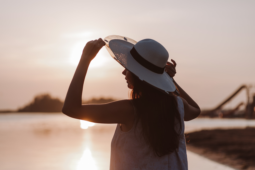 Silhouette of a woman in a wide brimmed hat at sunset